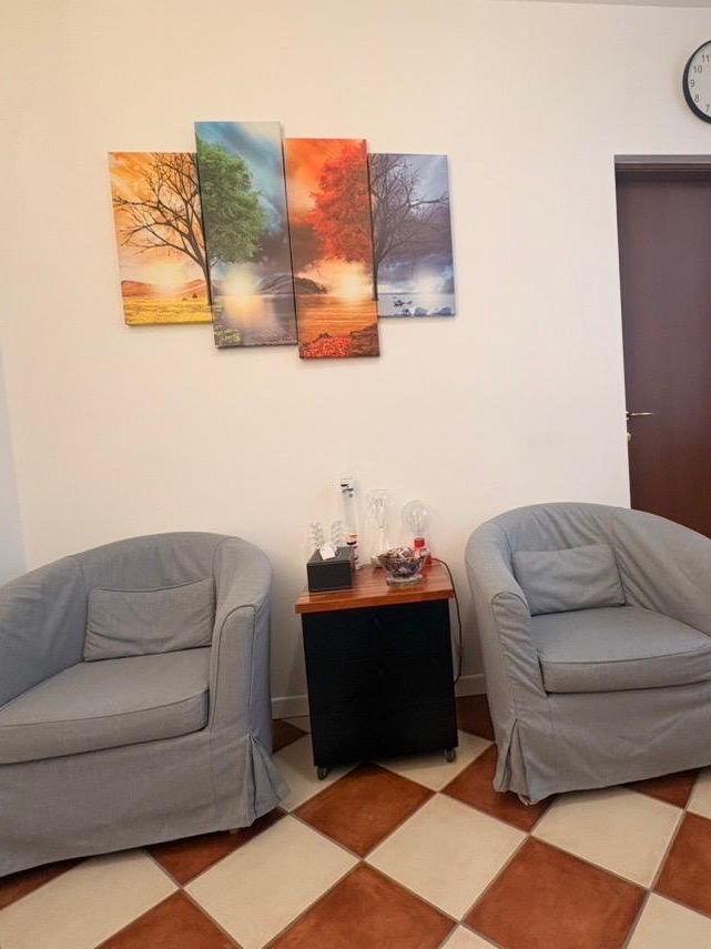 La sala d'attesa dello studio a Mantova: due poltrone e il quadro delle quattro stagioni